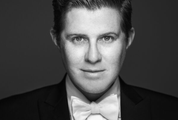 Black and white image of young man's head and shoulders in suit and bow tie